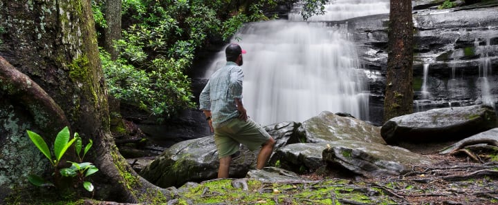 Man looking at waterfall in the woods